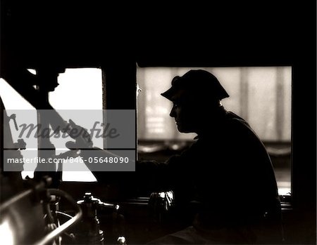 1920s - 1930s - 1940s SILHOUETTE TRAIN ENGINEER AT CONTROLS IN LOCOMOTIVE CAB OF RAILROAD STEAM ENGINE