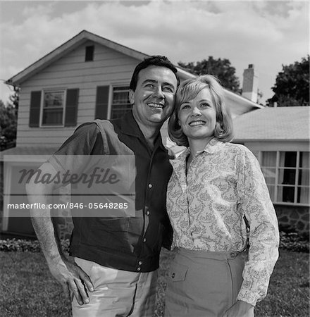 1960s HAPPY COUPLE PORTRAIT MAN WOMAN SMILING IN FRONT OF HOME