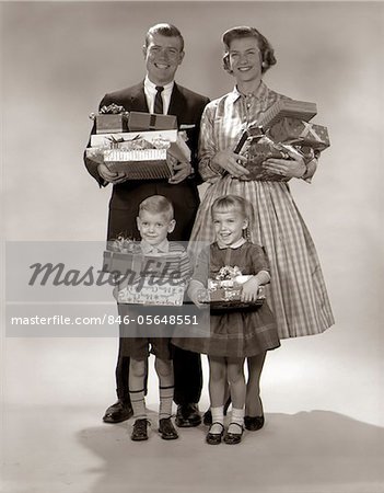 1960ER JAHRE FAMILY PORTRAIT VON VIER MUTTER VATER JUNGE MÄDCHEN TRAGEN WEIHNACHTSGESCHENKE VERPACKT PRÄSENTIERT