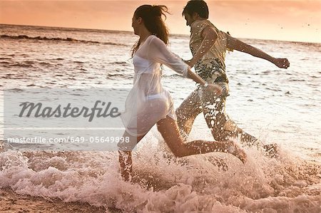 Couple running in waves at beach