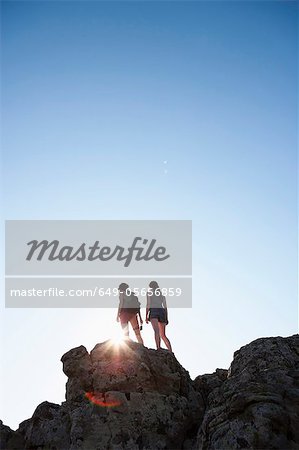 Silhouette of hikers standing on rock