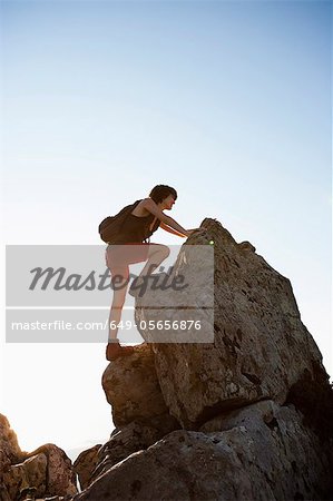 Hiker climbing rocks on hill