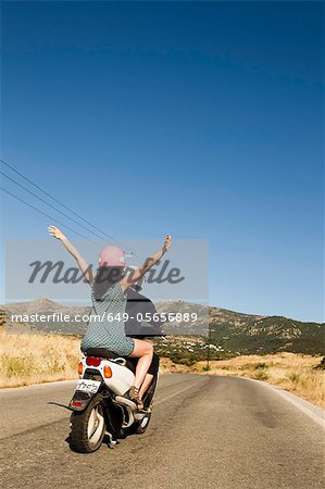 Women driving scooter on rural road