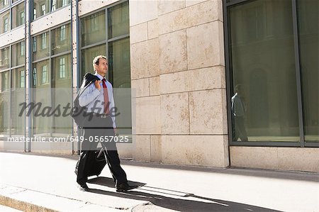 Businessman rolling luggage outdoors