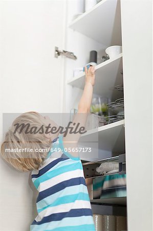 Boy reading for something in cabinet