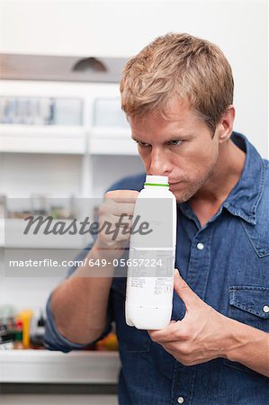 Man smelling milk jug for freshness