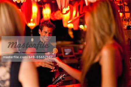 Bartender handing woman a cocktail Bartender handing woman a cocktail