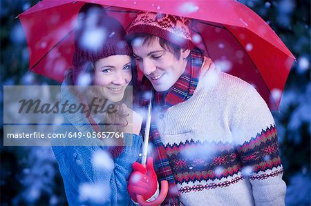 Smiling couple under umbrella in snow