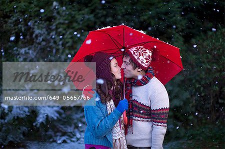 Couple souriant sous le parapluie dans la neige