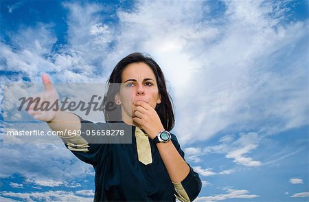 Woman blowing whistle against blue sky