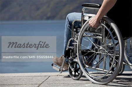 Homme en fauteuil roulant assis près de l'eau