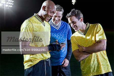 Soccer players looking at cellphone on pitch