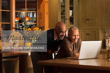 Mature couple using laptop in kitchen