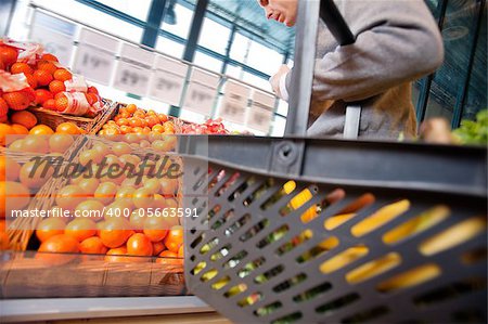Closeup of a man carrying basket while buying fruits in the supermarket
