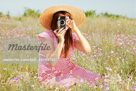 Retro style girl at countryside with camera.