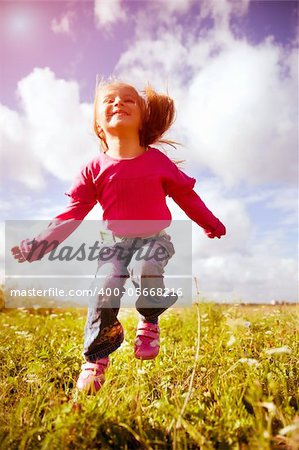 Little girl jumping against a beautiful sky