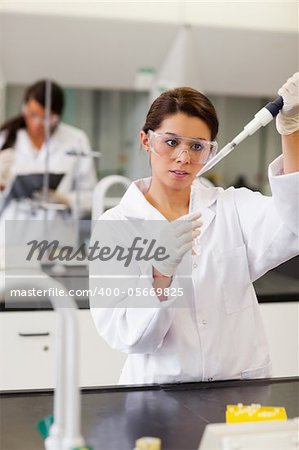 Portrait of a focused student pouring a liquid in a tube in a laboratory