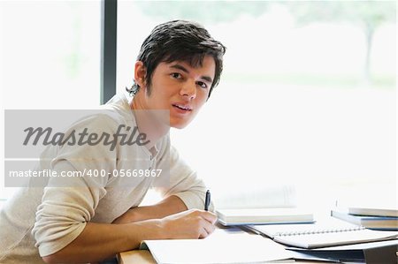 Handsome student writing a paper in a library