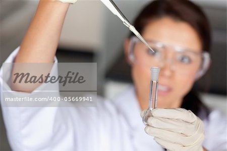 Young brunette woman pouring a liquid in a tube in a laboratory