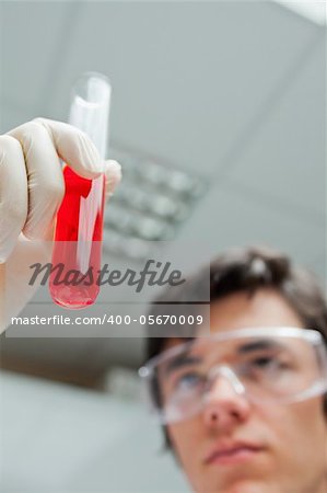 Portrait of a scientist looking at a test tube with the camera focus on the object