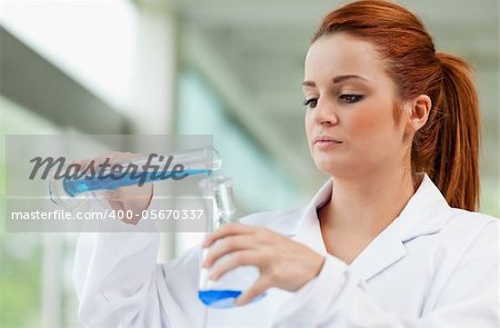 Young scientist pouring blue liquid in an Erlenmeyer flask in a laboratory