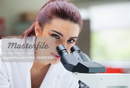 Close up of a young scientist posing with a microscope in a laboratory