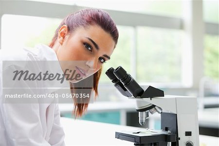 Brunette posing with a microscope while looking at the camera