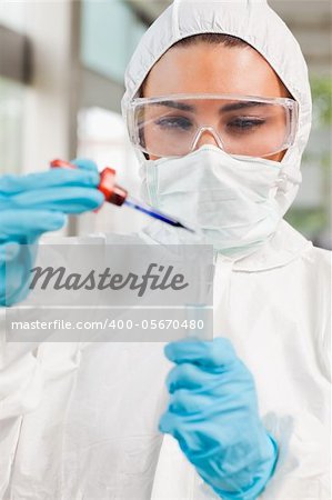 Portrait of a protected science student dropping a liquid in a test tube in a laboratory