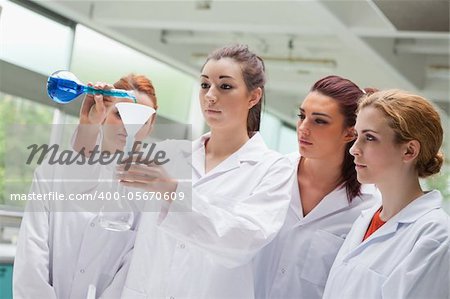 Female science students pouring liquid in a flask in a laboratory