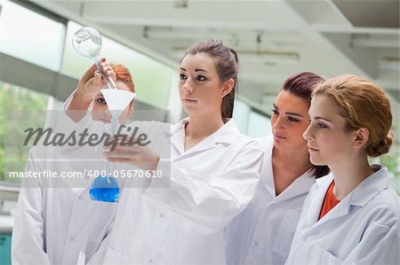 Cute science students pouring liquid in a flask in a laboratory
