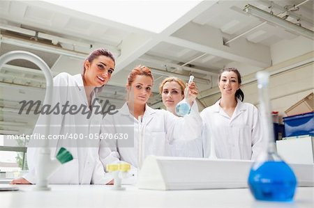 Smiling chemistry students holding a flask while looking at the camera