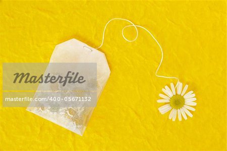 Bag of chamomile tea over yellow handmade paper - concept