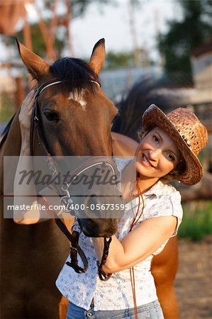 Woman in hat embrace brown horse