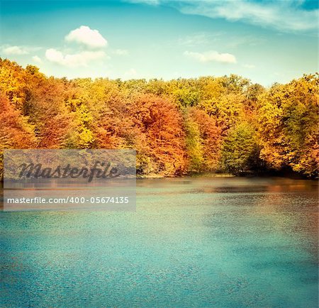Nature landscape with beautiful lake in autumn with colorful trees and blue sky with cloudscape in the background.