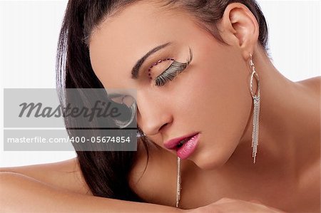 portrait of pretty and sensual brunette with hair tail and creative make up with long eyelashes and earrings in ears posing