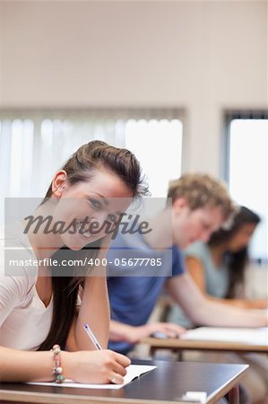 Portrait of a smiling woman writing  in a classroom