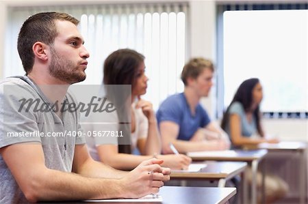 Handsome young man listening in a classroom