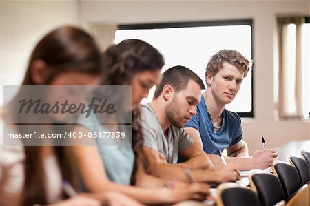 Students listening a lecturer with the camera focus on the foreground in an amphitheater