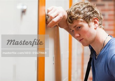 Close up of a lonely student leaning on a locker in a corridor