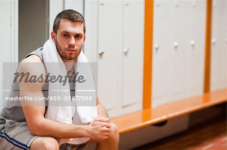 Handsome sports student sitting on a bench with a towel