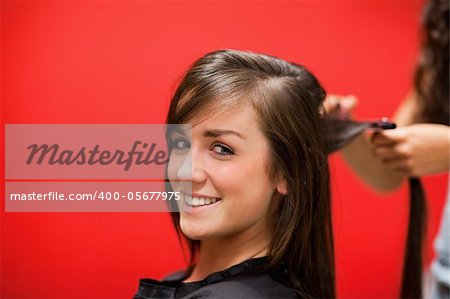 Young woman having her hair straightened while looking at the camera