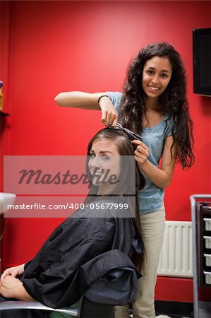 Portrait of a happy hairdresser cutting hair while looking at the camera
