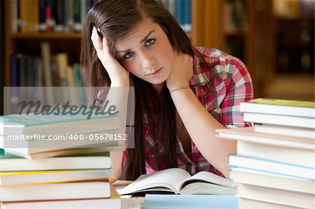 Depressed student surrounded by books looking at the camera