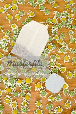 Bag of chamomile tea with dry chamomilla flowers over wooden background