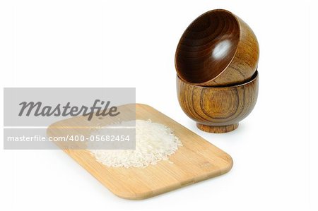 Wooden bowls for rice. A handful of rice on a wooden board.