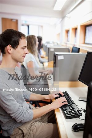 Serious male student working with a computer in an IT room