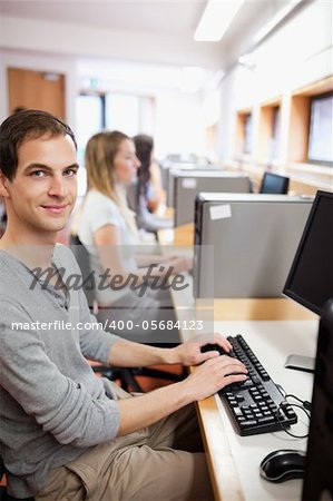 Portrait of a serious male student working with a computer in an IT room