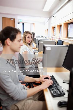 Portrait of a young male student posing with a computer in an IT room