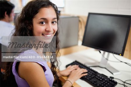 Smiling brunette student posing with a computer in an IT room