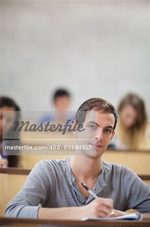 Portrait of students taking notes in an amphitheater with the camera focus on the foreground